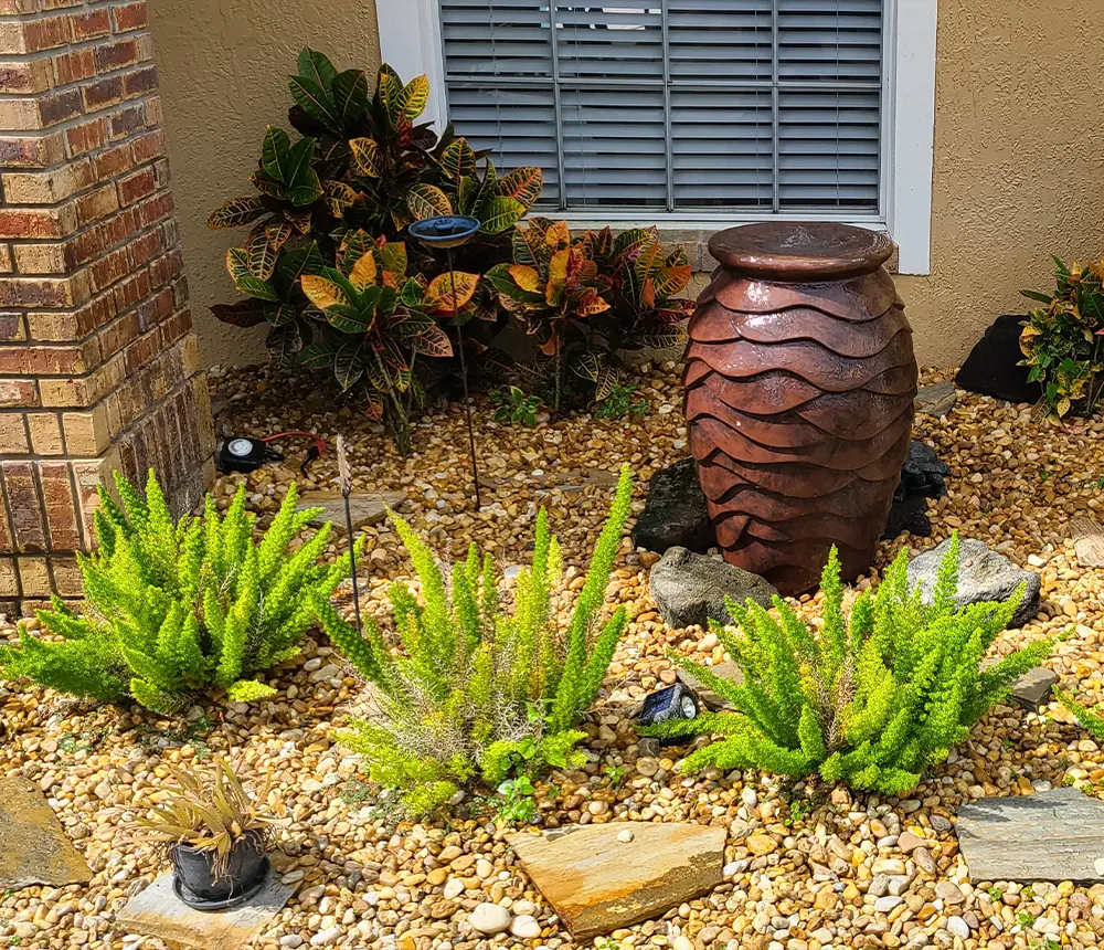 Small low water use landscaping with a water feature, pebbles, and native FL plants
