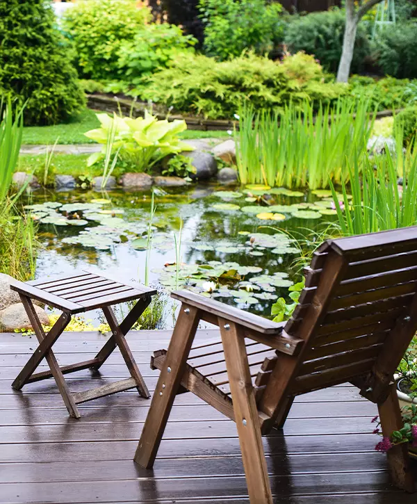 Two wooden chairs near the pond