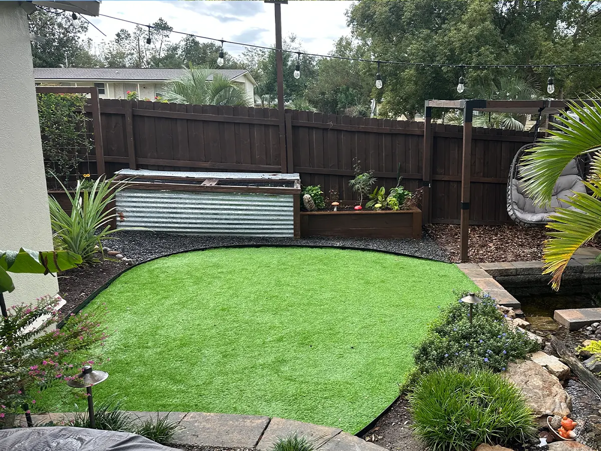 Artificial turf installation in backyard with seating area and decorative plants