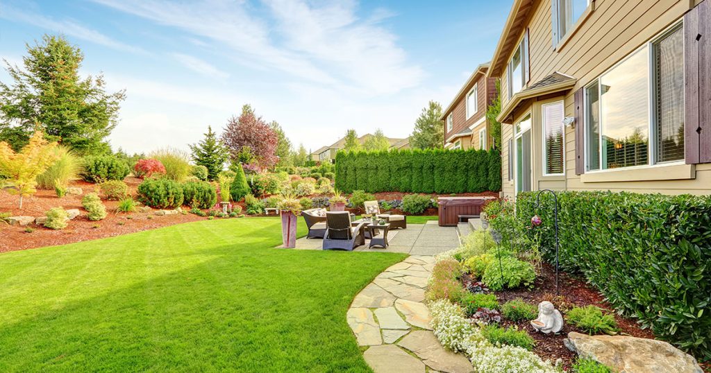 Beautiful backyard landscaping with lush green lawn, stone pathway, and outdoor seating